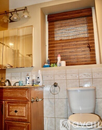 A white toilet sits next to a wooden cabinet in a bathroom.