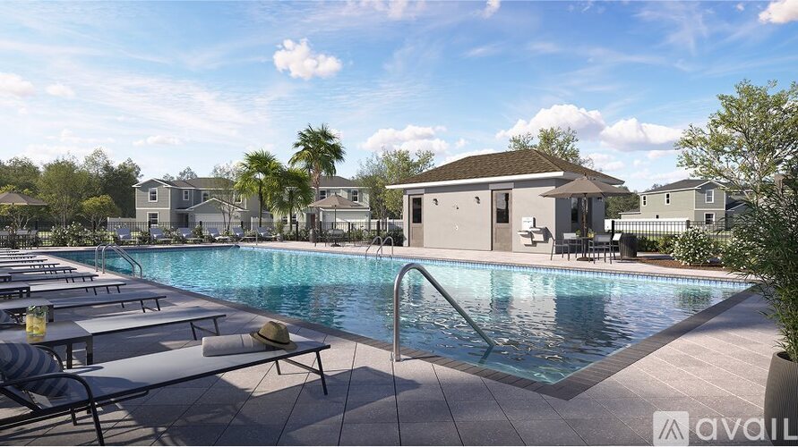 A pool area with sun loungers and a building in the background.