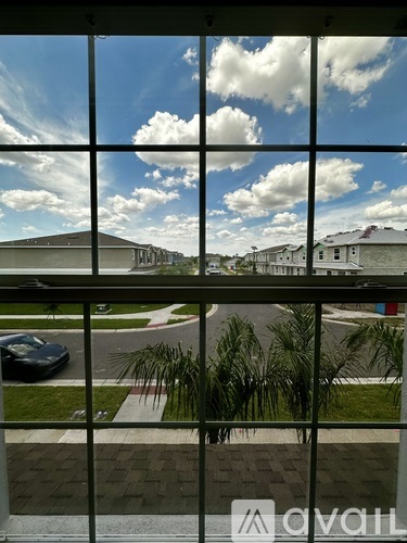 A view from inside a building looking out through a window at a car and buildings.