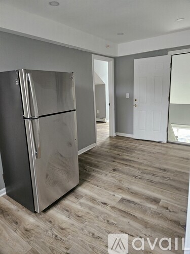 A stainless steel refrigerator in a room with wooden flooring.
