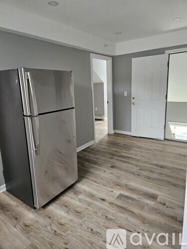 A stainless steel refrigerator in a room with wooden flooring.