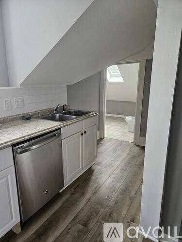 A kitchen with a stainless steel dishwasher and white cabinets.
