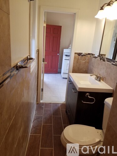 A bathroom with a toilet, sink and a red door.