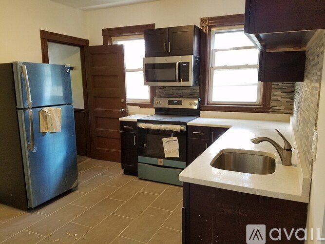 A kitchen with a blue fridge, black oven, and a white sink.