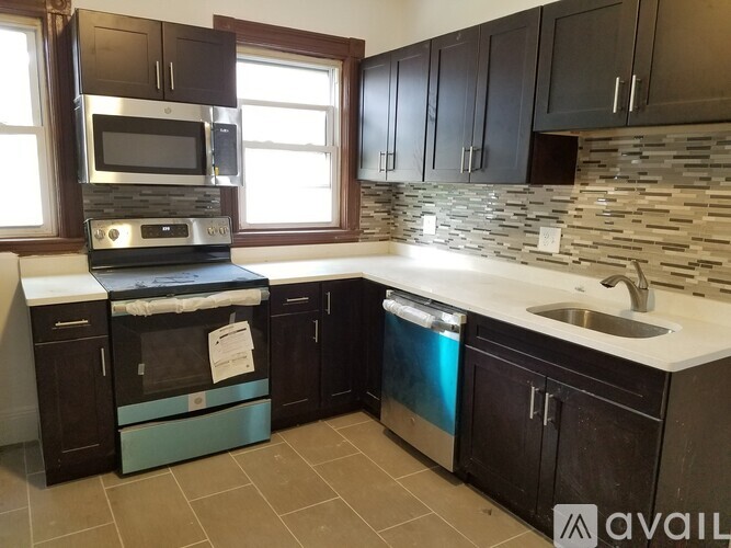 A kitchen with black cabinets and a stone backsplash.