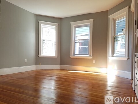 A room with wooden floors and two windows.