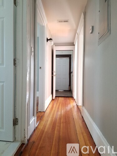 A hallway with wooden floors and white walls.