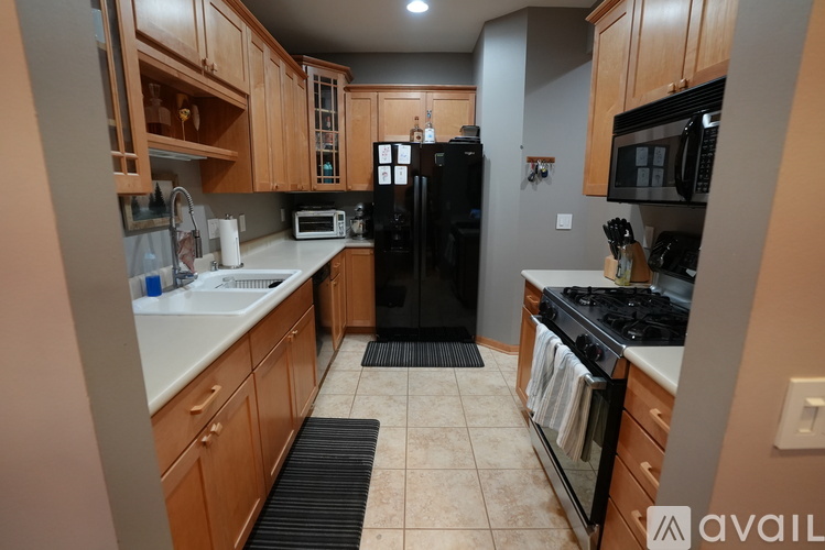 A kitchen with wooden cabinets and a black refrigerator.