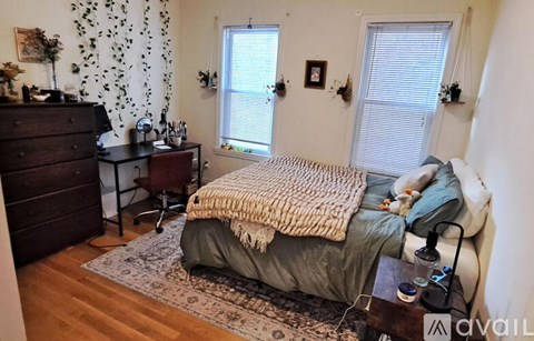 A bedroom with a bed covered in a blanket and a wooden dresser.