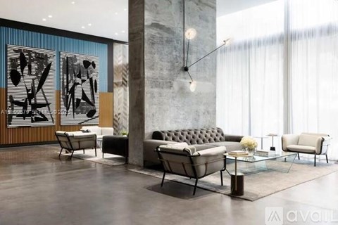 A modern living room with a grey sofa, a glass table, and a large abstract painting on the wall.
