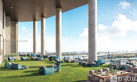 A modern outdoor seating area with green cushioned chairs and tables is set up on a grassy area under a series of tall columns.