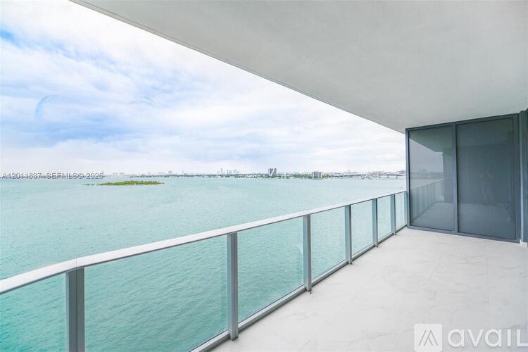 A balcony with a glass railing overlooking a body of water.
