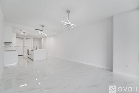 A spacious, empty room with a marble floor and a chandelier hanging from the ceiling.