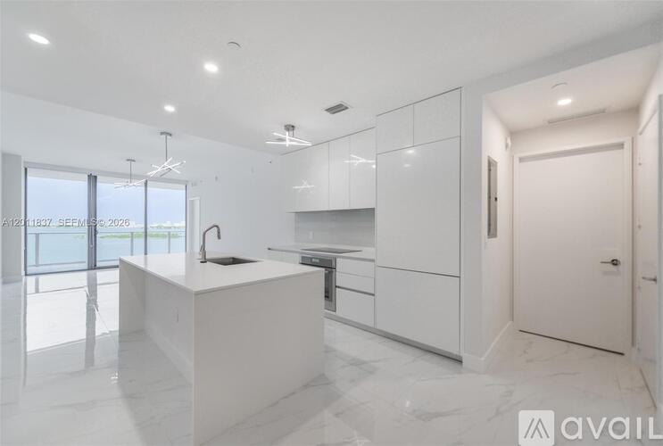 A modern kitchen with white cabinets and a marble countertop.
