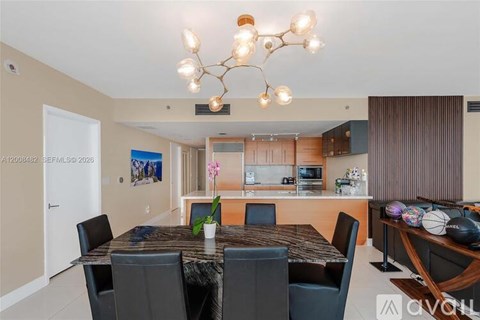 A dining room with a table set for four and a chandelier hanging from the ceiling.