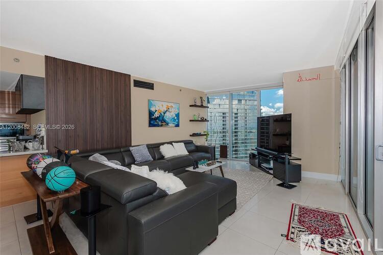 A living room with a black leather couch and a basketball on a wooden table.