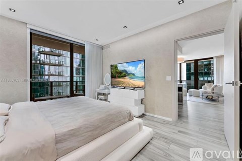 A bedroom with a large bed and a flat screen TV mounted on the wall.