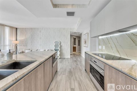 A modern kitchen with wooden cabinets and a marble countertop.