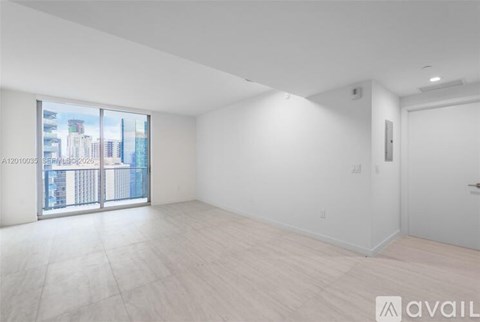 A spacious, empty room with a view of the cityscape outside the window.