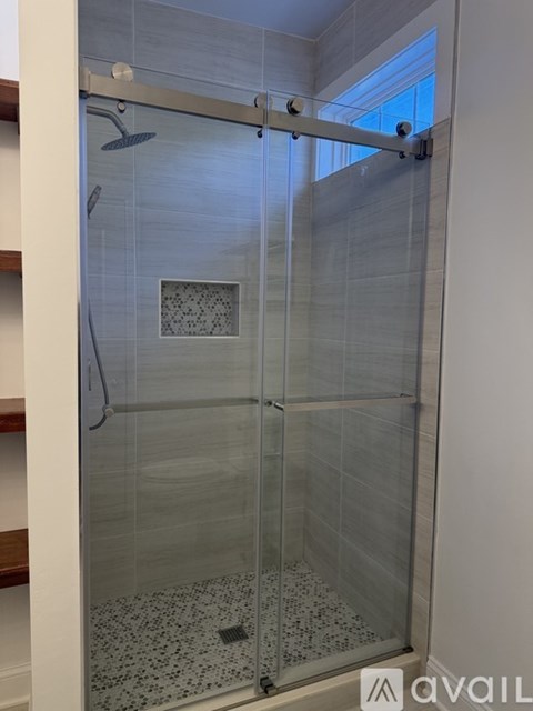 A shower with a glass door and a tiled floor.