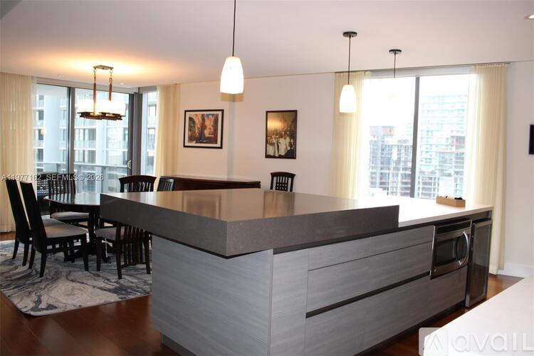 A modern kitchen with a large island and a dining table.