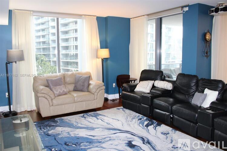 A living room with a beige couch and a black leather couch.