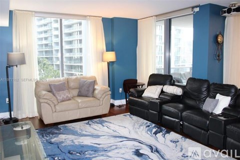 A living room with a beige couch and a black leather couch.