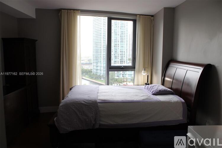 A bedroom with a large bed and a window overlooking a cityscape.