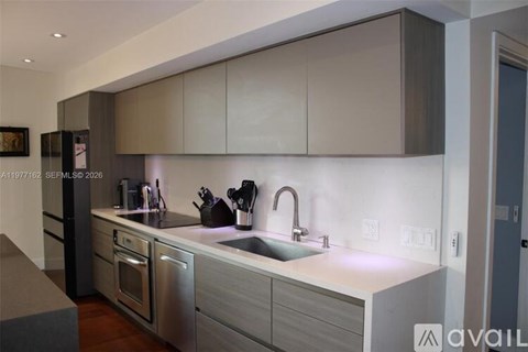A modern kitchen with a stainless steel refrigerator and a white countertop.