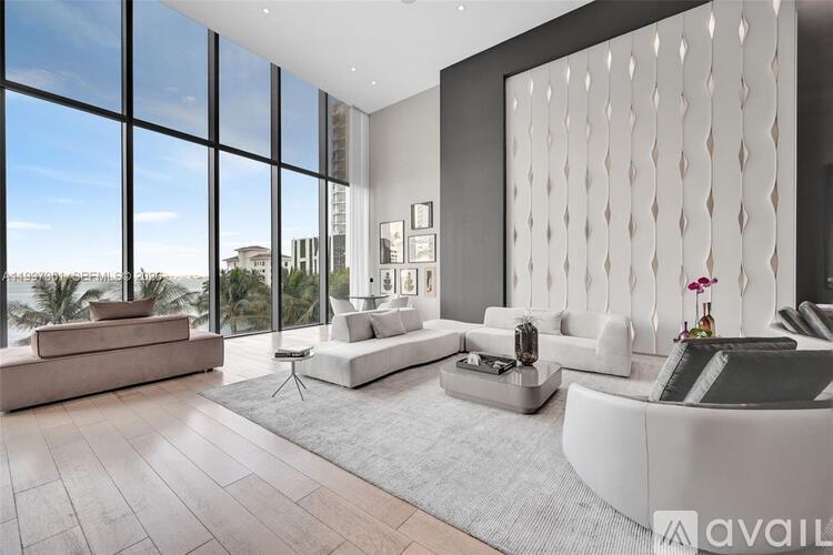 A modern living room with a large window overlooking a beach.