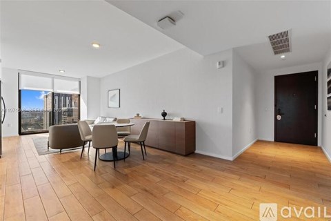 A modern dining room with a wooden floor and a glass door leading to a balcony.
