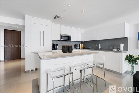 A modern kitchen with white cabinets and a bar area.
