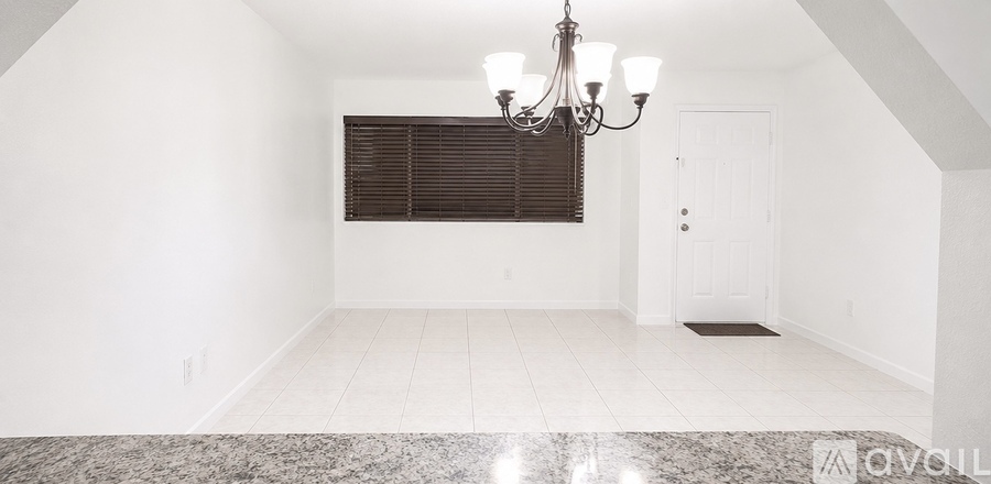A spacious room with a chandelier and a marble table.