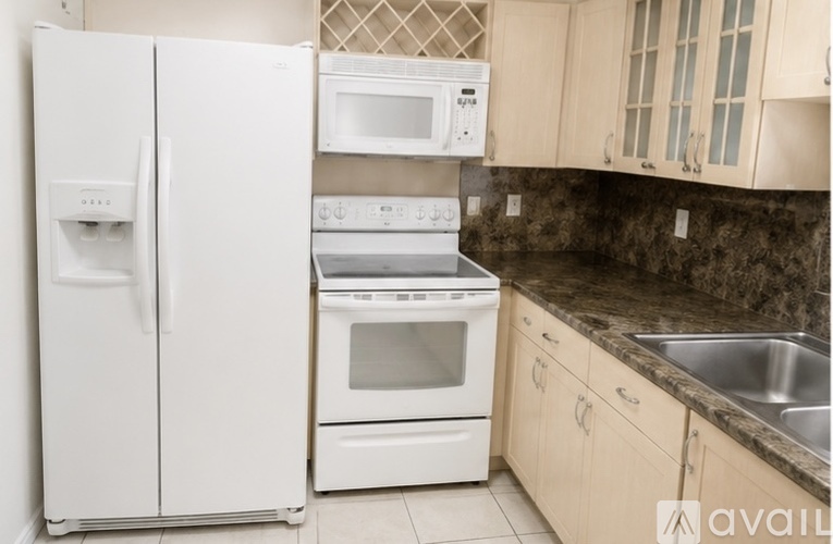 A kitchen with a white refrigerator, microwave, oven, and sink.