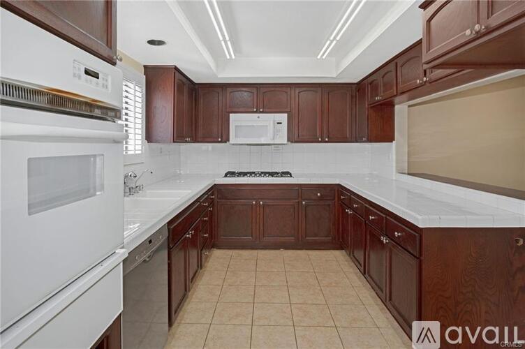 A kitchen with brown cabinets and white appliances.
