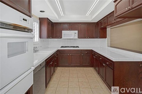 A kitchen with brown cabinets and white appliances.