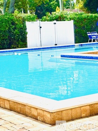 A small pool with a white fence in the background.