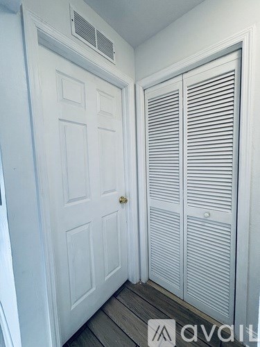A white door with a closed white shuttered window to the right.