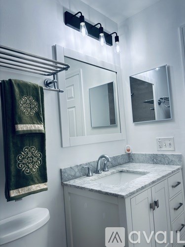 A bathroom with a white sink and a green towel hanging on the towel rack.