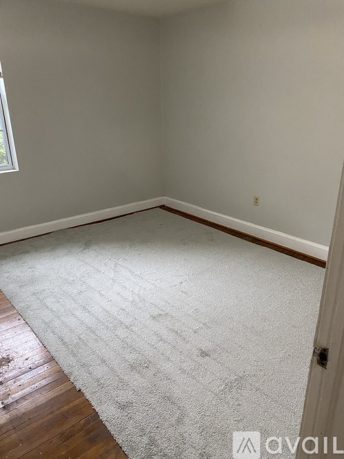 A room with a carpeted floor and a door on the right side.