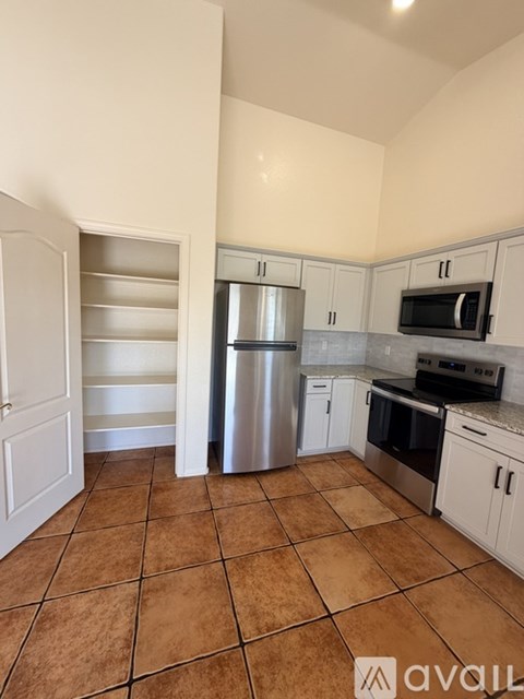 A kitchen with white cabinets and a tile floor.