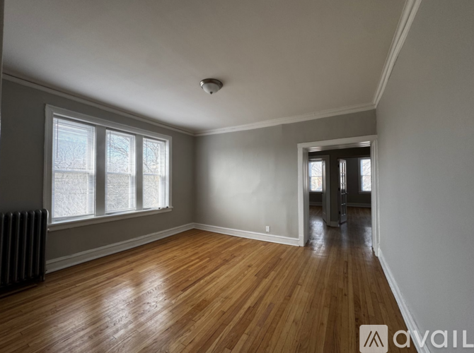 A room with wooden floors and a window with a view of a snowy landscape.