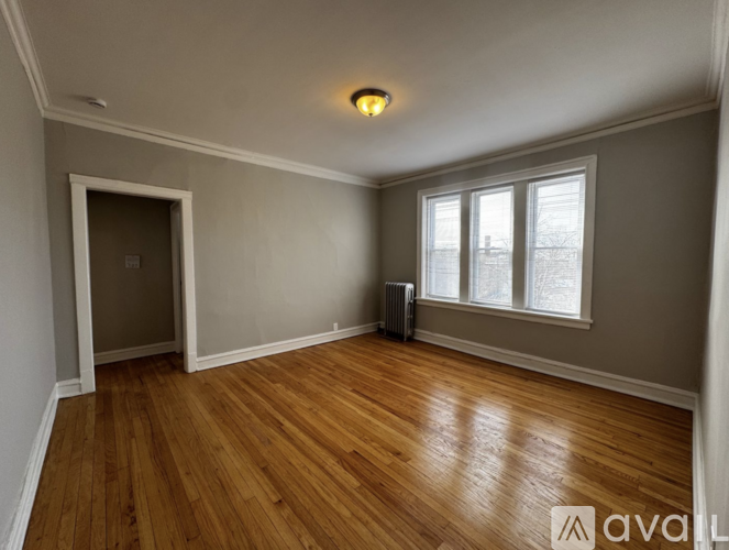 A room with wooden floors and a window with white curtains.