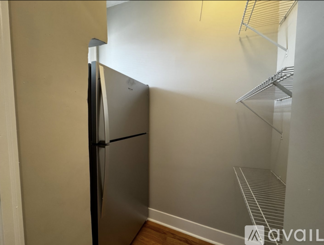 A small kitchen with a refrigerator and a shelf.