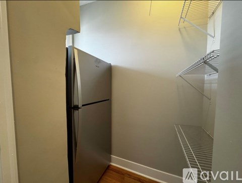 A small kitchen with a refrigerator and a shelf.