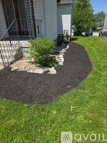 A white house with a black mulch garden bed in front.