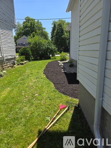 A yard with a black mulch bed and a red flag.