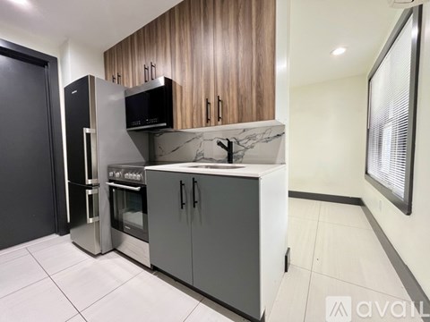 A kitchen with a black fridge, microwave, and oven, and a white countertop with a marble top.