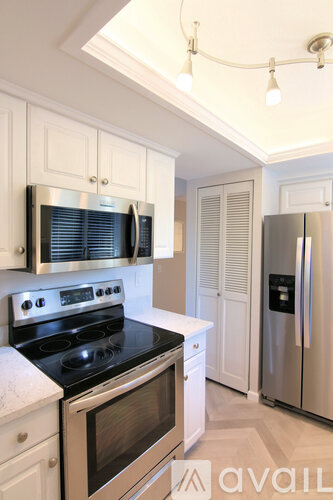 A kitchen with white cabinets and a stainless steel refrigerator.