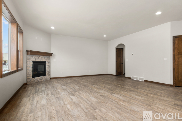 A spacious room with a fireplace and wooden flooring.